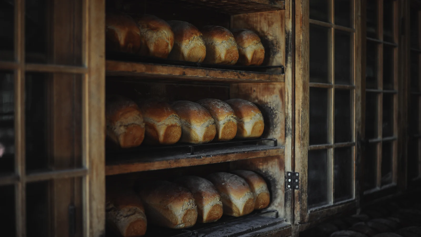 Loaves of bread resting on the wooden shelves of an old bakery cabinet